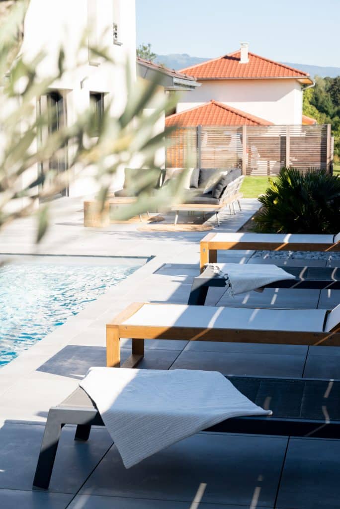 Vue coupée d'un extérieur de terrasse moderne avec piscine sous ciel ouvert ensoleillé par architecte d'intérieur Annecy