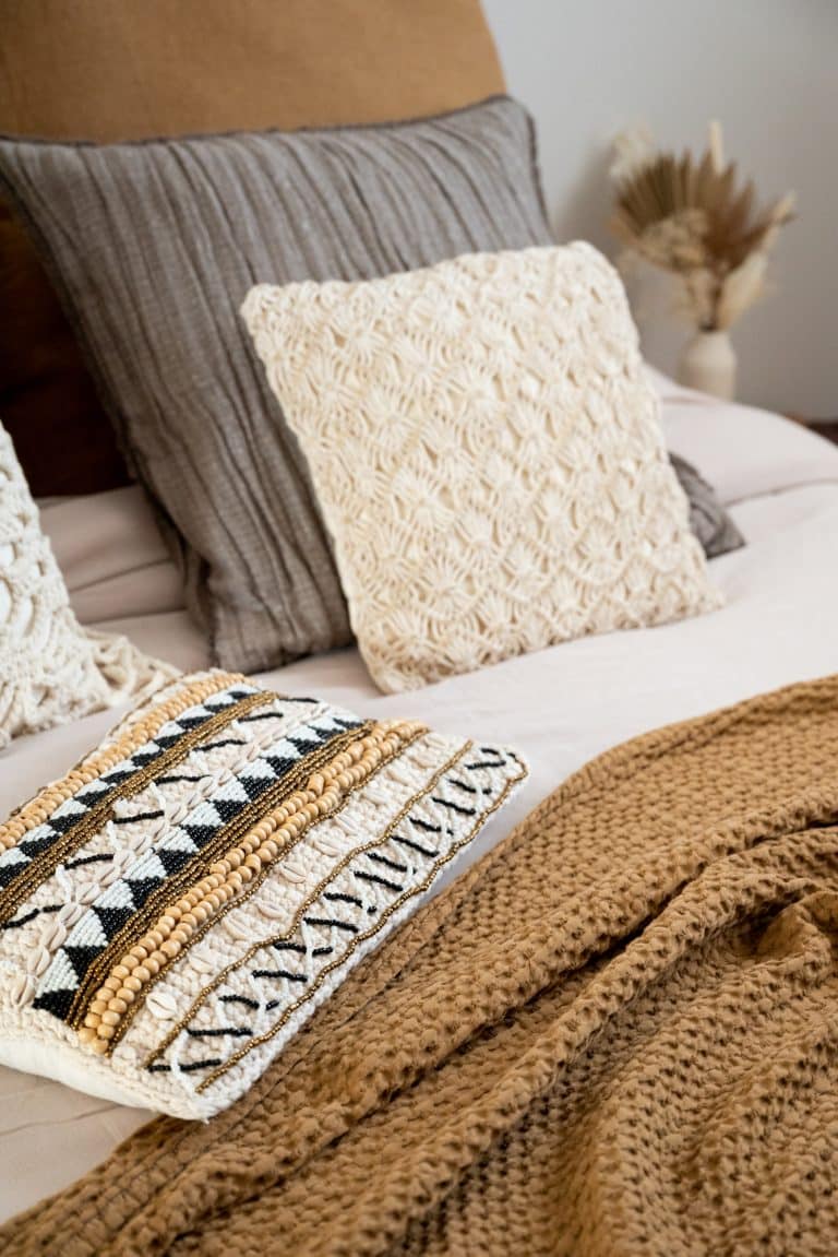 Gros plan sur ornement d'inspiration ethnique d'un coussin sur lit de chambre à coucher imaginés par une architecte d'intérieur Annecy